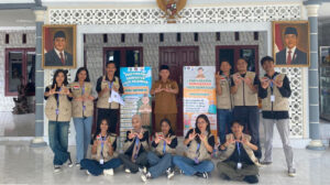 Mahasiswa PMT Kelompok 19 dan Kepala Desa, serta Banner hasil karya mereka