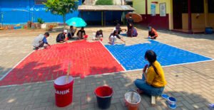Mahasiswa Kelompok 1 Soekarno Fakultas Ilmu Pendidikan (FIP) Universitas Tribhuwana Tunggadewi (UNITRI) Malang sedang melaksanakan pengecatan lapangan bola voli di SDN 1 Jedong, Kecamatan Wagir, Kabupaten Malang